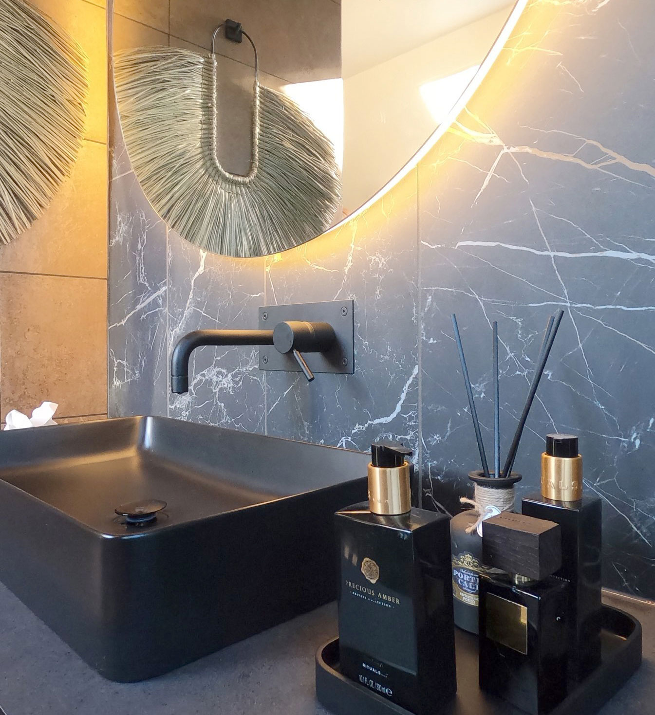 Bad med sort vask, blandebatteri og detaljer. Marmorerte mørke fliser.